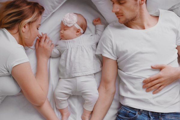 young couple sleeping with a baby girl