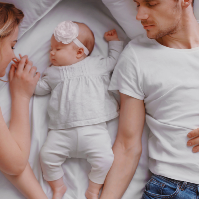 young couple sleeping with a baby girl