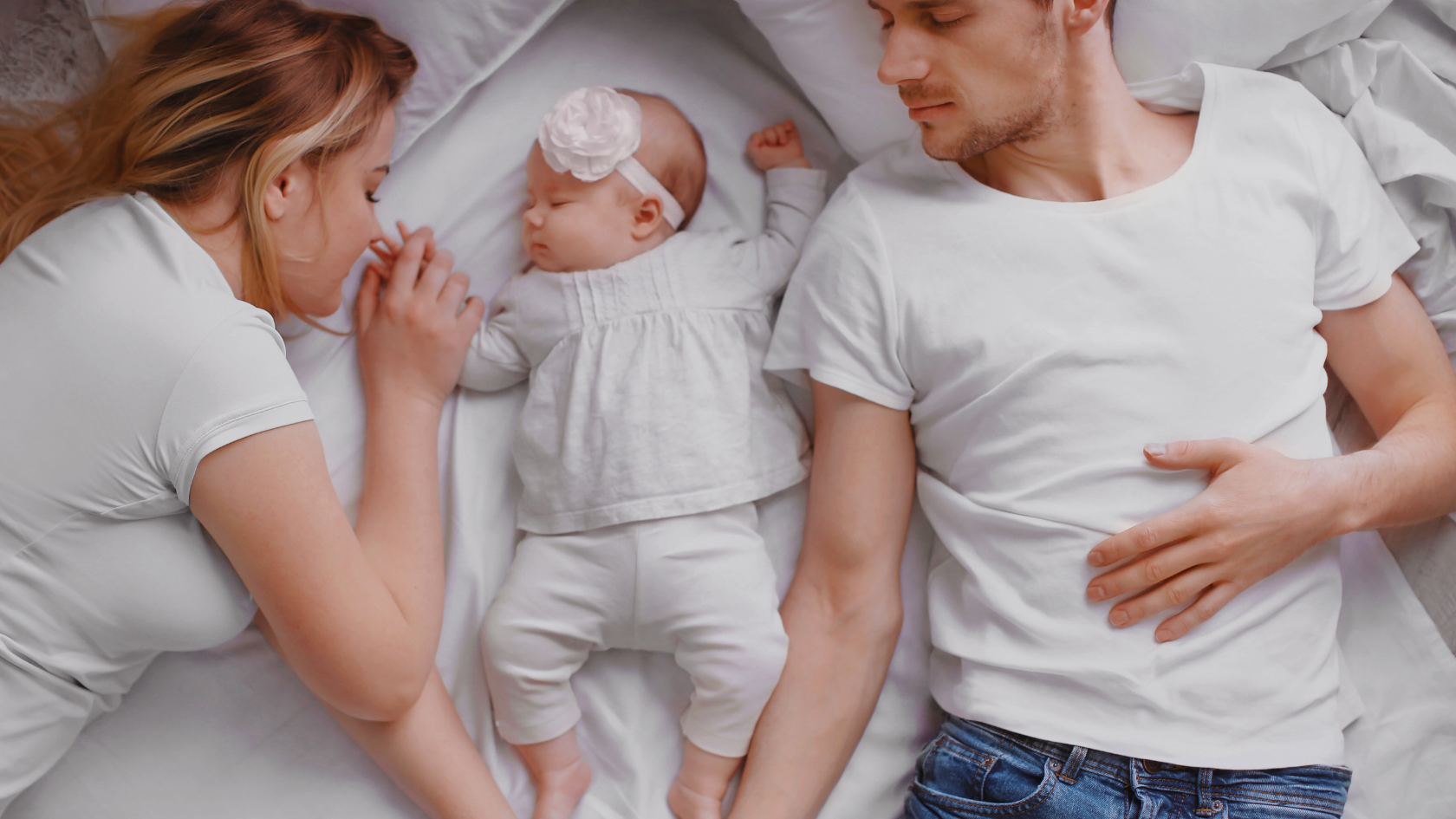 young couple sleeping with a baby girl